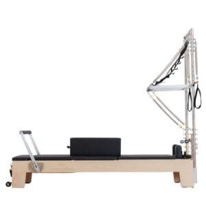 Reformer de Pilates en madera de haya con torre y tapicería negra fabricado por Living by Pilates